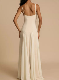 Woman wearing a long, light-colored dress with thin straps on a beige background