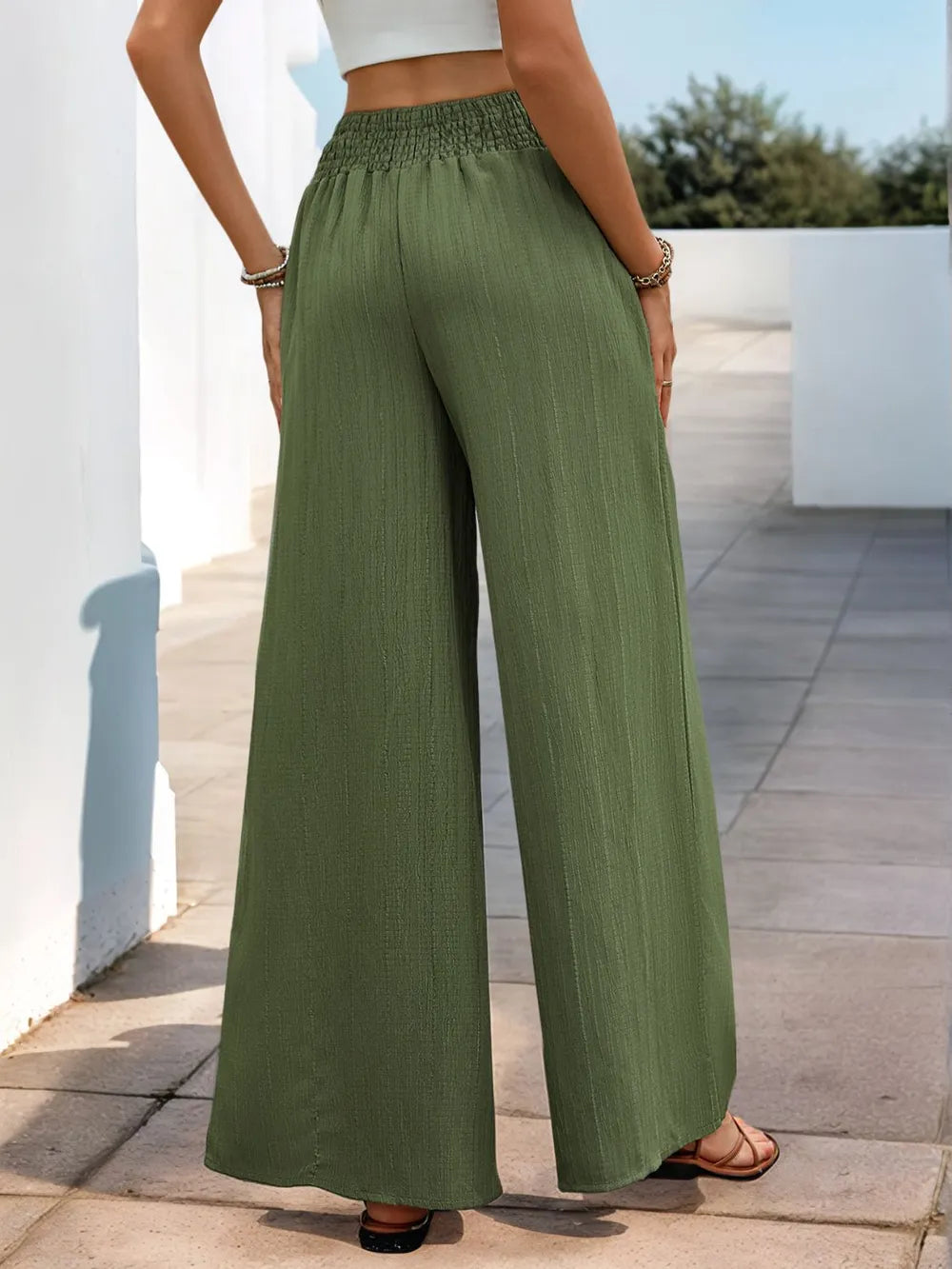 Person wearing green wide-leg pants and a white top outdoors.