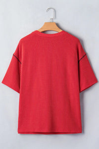 Red ribbed sweater on a wooden hanger against a light gray background