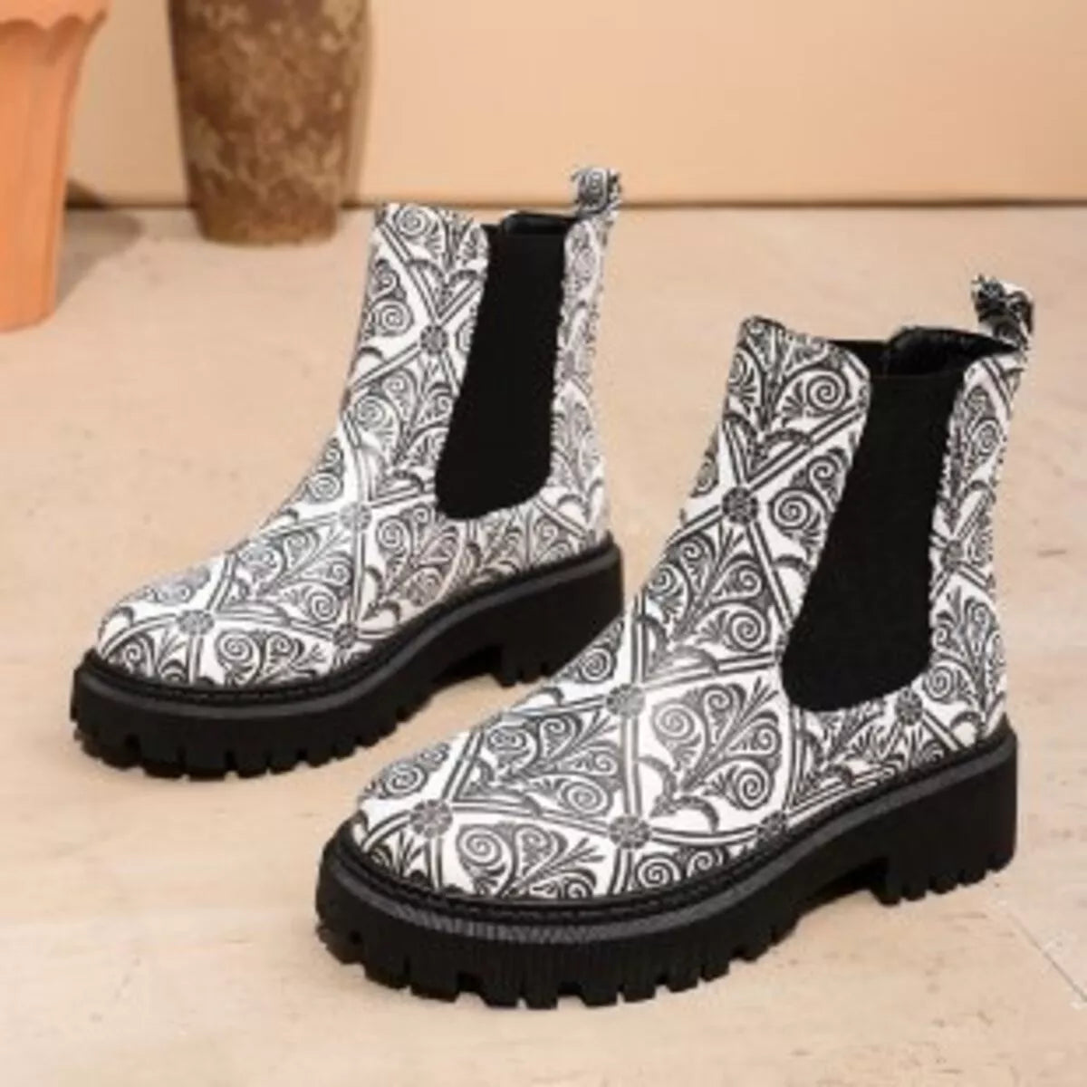Pair of black and white patterned boots on a beige surface.