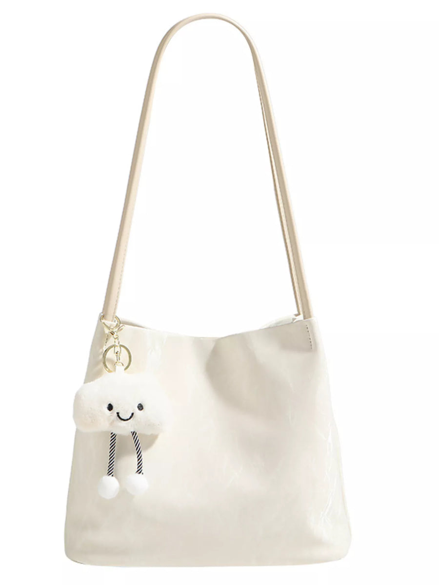 White shoulder bag with a plush toy on a white background