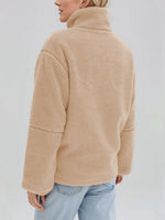 Person wearing a beige fleece jacket on a plain background