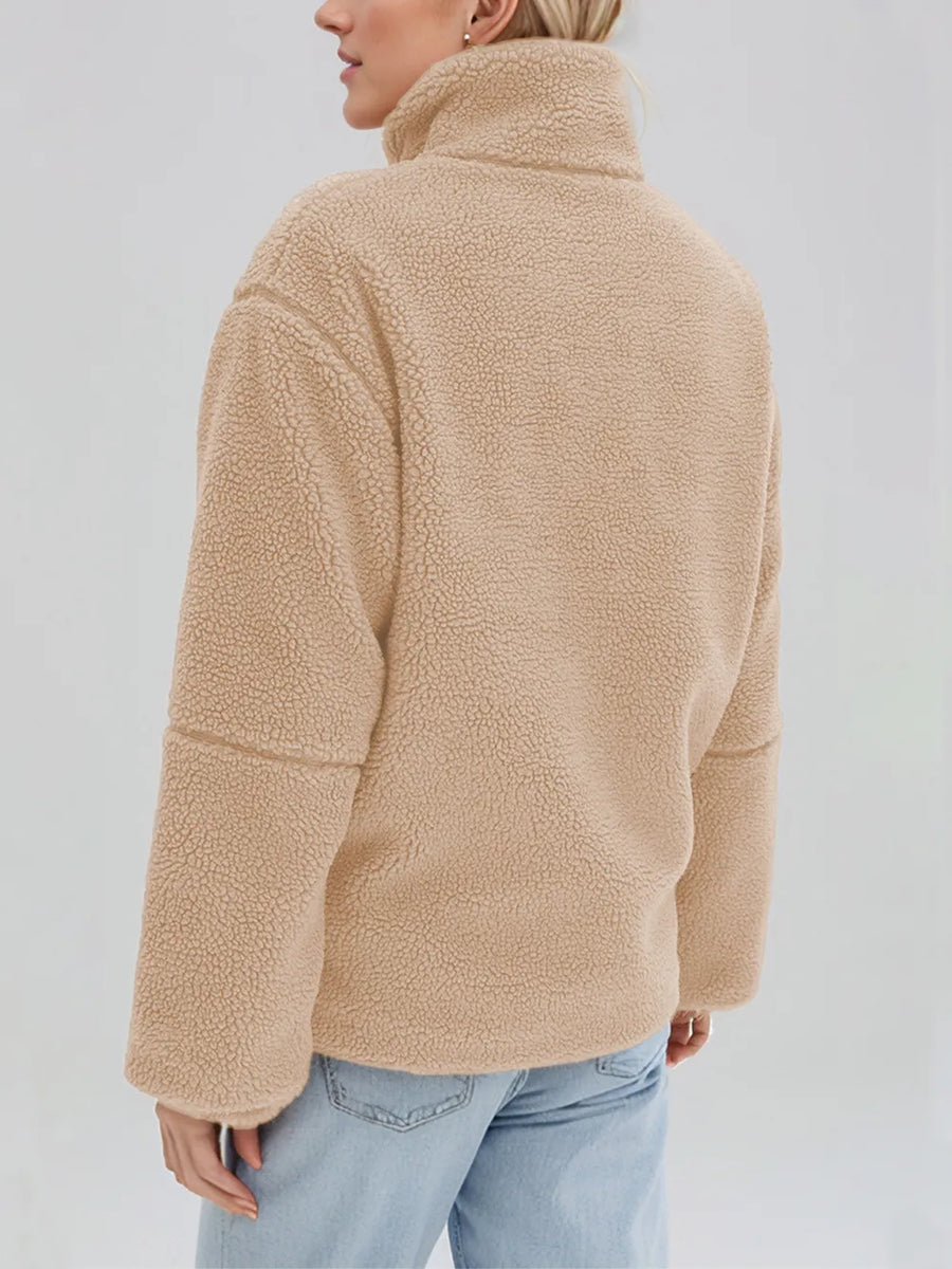 Person wearing a beige fleece jacket on a plain background