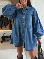 Woman wearing a blue denim dress in an indoor setting