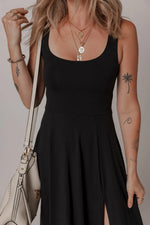 Person wearing a black dress with tattoos on arms holding a white handbag.