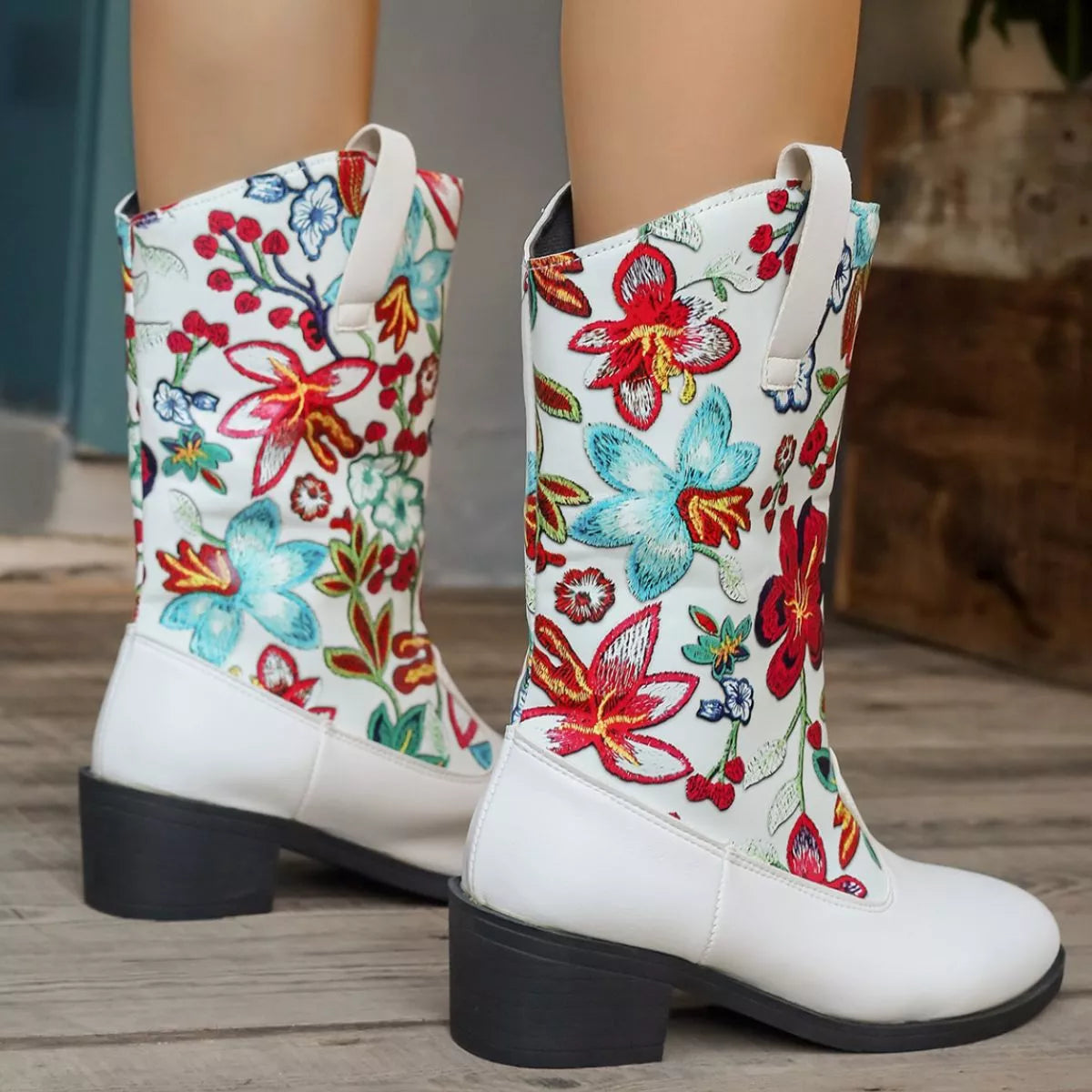 White boots with colorful floral patterns on a wooden floor.