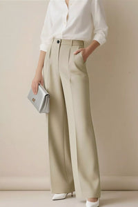 Person wearing a white shirt and beige wide-leg pants against a plain background