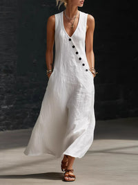Woman wearing a white sleeveless dress with black buttons against a dark background