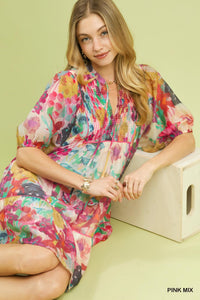Woman wearing a colorful floral dress sitting on a light green background