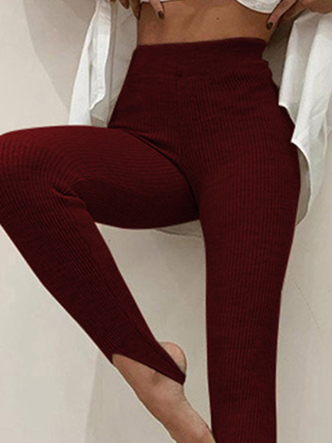 Maroon ribbed leggings worn by a person sitting on a white surface.
