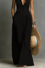 Person wearing a black sleeveless jumpsuit holding a straw hat against a gray background