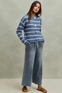 Woman wearing a blue striped sweater and jeans against a neutral background