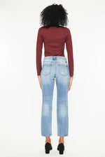 Person wearing a burgundy long-sleeve top and light blue jeans on a white background