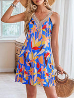 Woman wearing a colorful floral dress with a straw hat and bag indoors.
