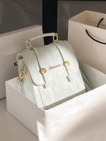 Light green handbag with gold accents on a white box