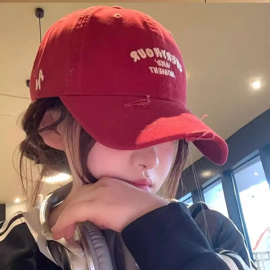 Person wearing a red cap with text, indoors.