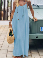 Woman in a long light blue dress holding a woven bag, standing next to a vehicle.
