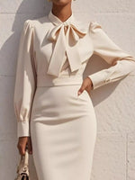 Beige dress with a large bow tie against a light background