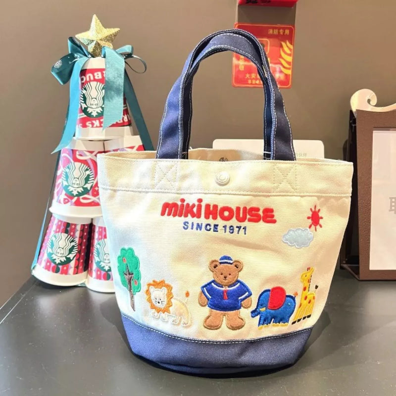 Children's tote bag with cartoon designs and 'miki HOUSE' branding on a table.