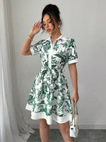 Woman wearing a green and white floral dress against a plain background