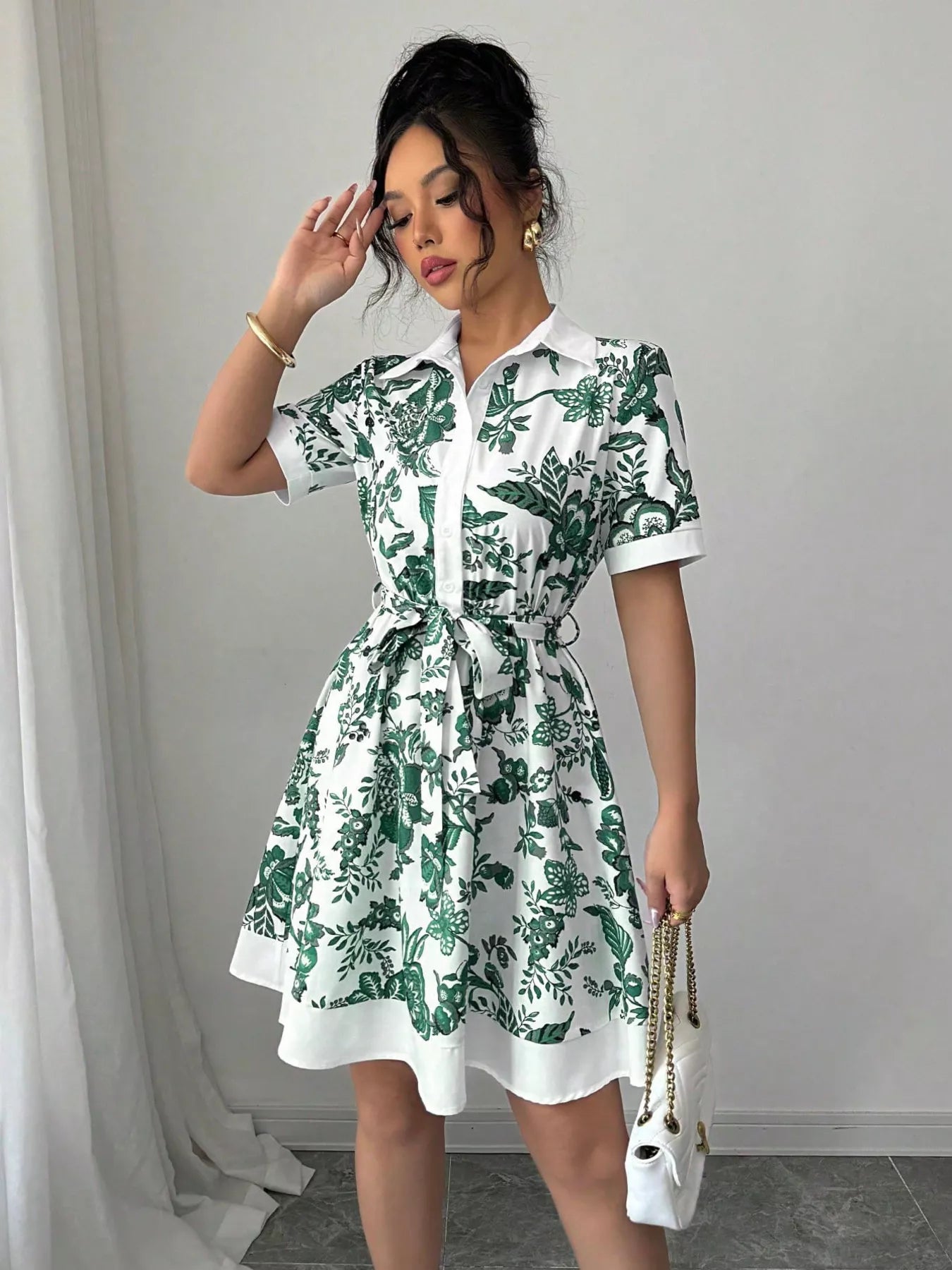 Woman wearing a green and white floral dress against a plain background