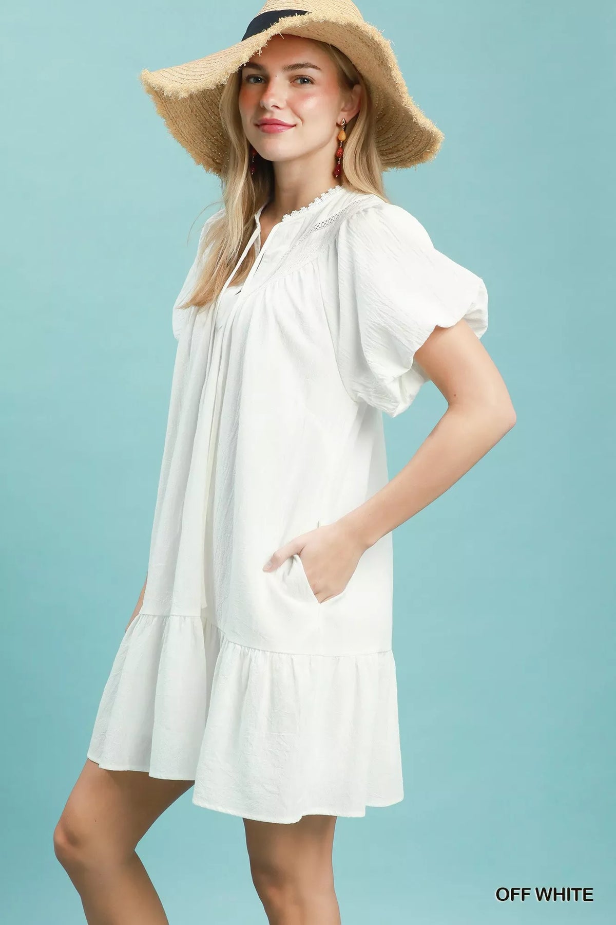 Woman wearing a white dress and straw hat against a light blue background