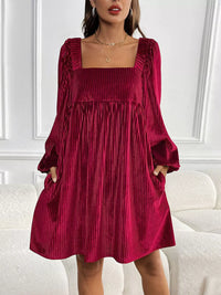 Woman wearing a burgundy pleated dress in an indoor setting