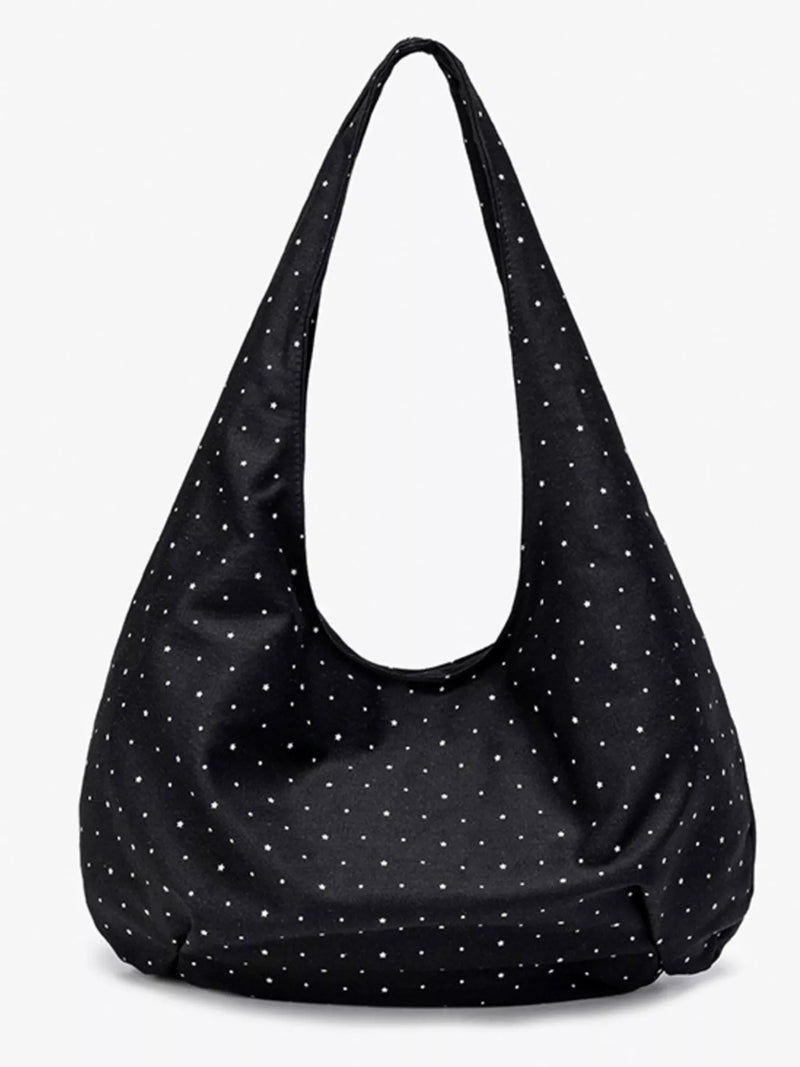 Black shoulder bag with white polka dots on a white background