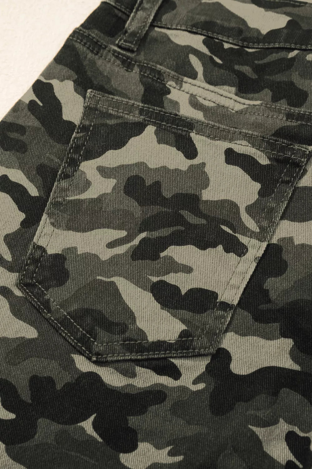 Close-up of camouflage-patterned pants with a pocket detail.