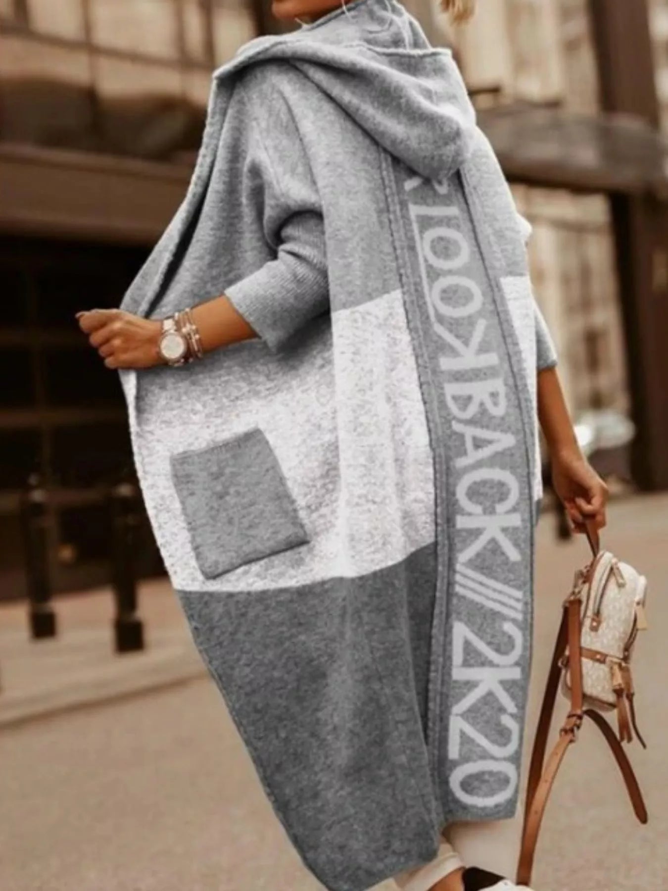 Person wearing a gray oversized sweater with 'Lookbook 2k20' text, holding a beige handbag.
