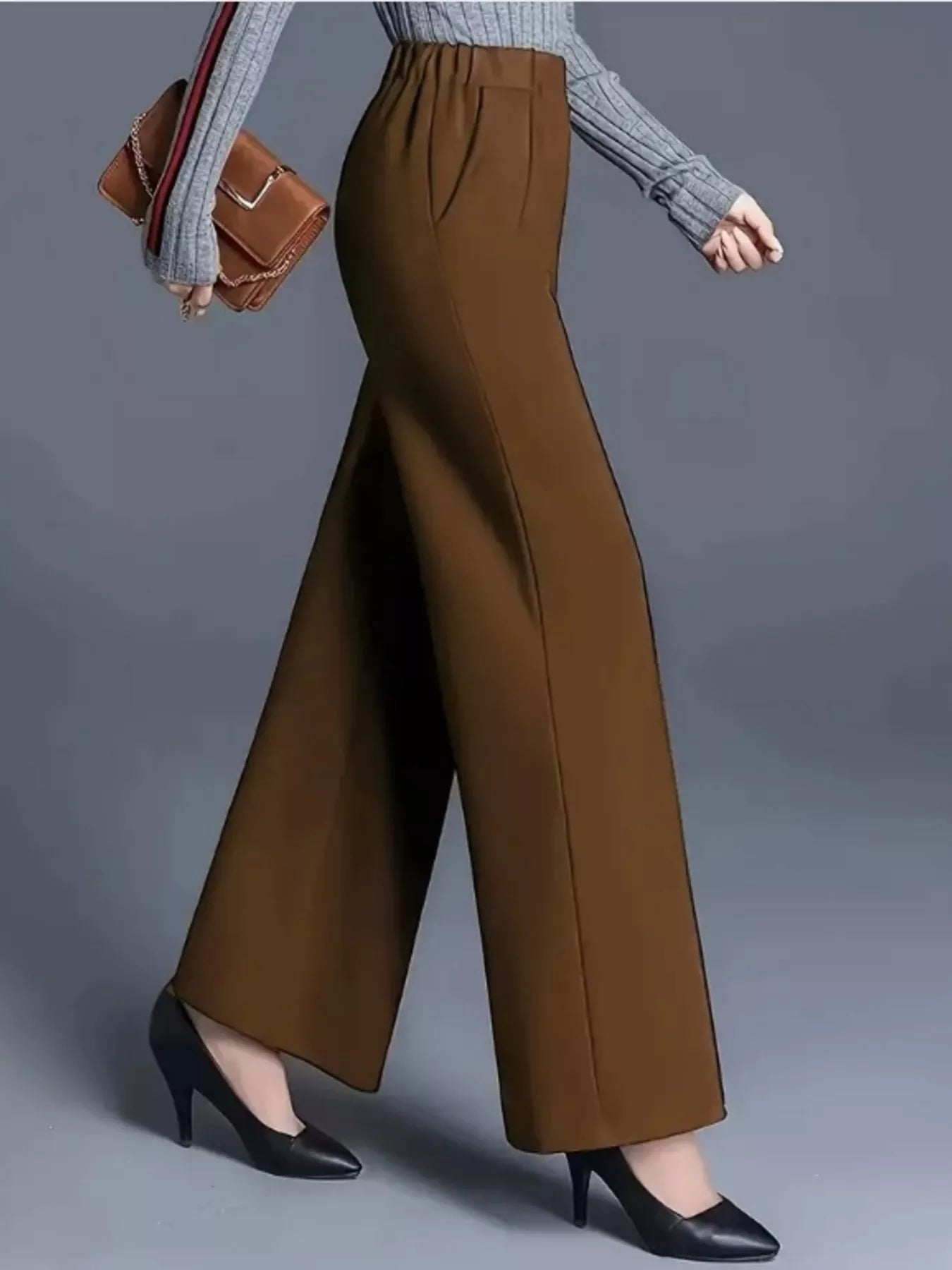 Brown wide-leg pants worn with a gray sweater and black shoes on a gray background