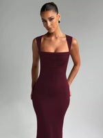 Woman wearing a burgundy evening gown against a gray background