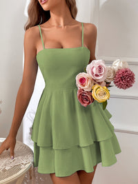 Woman wearing a green dress holding a bouquet of flowers indoors.