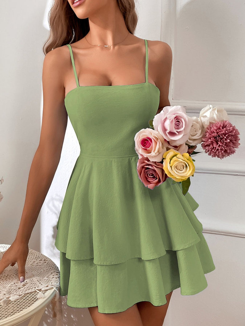 Woman wearing a green dress holding a bouquet of flowers indoors.