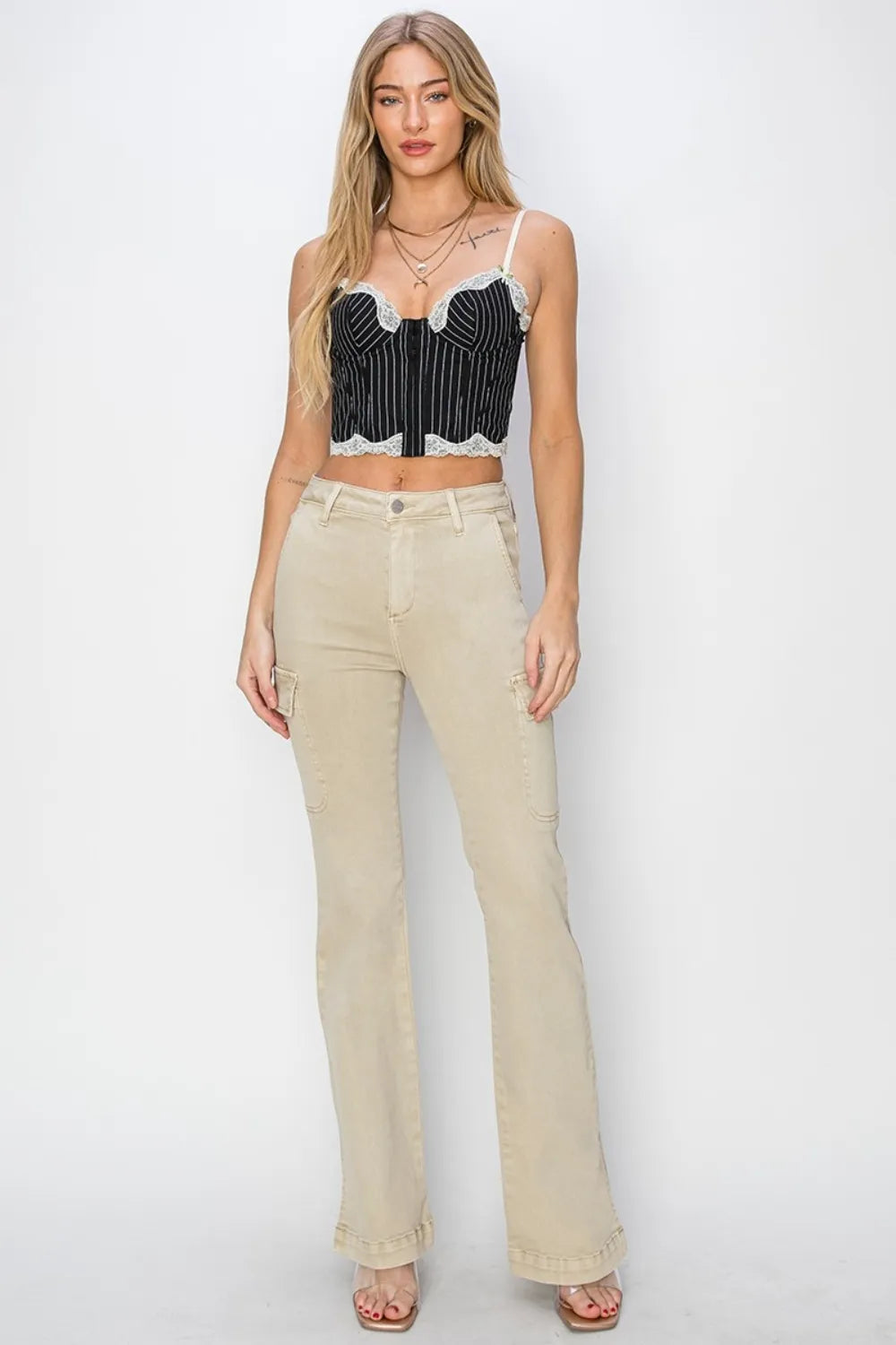 Woman wearing a black and white patterned crop top and beige pants on a white background