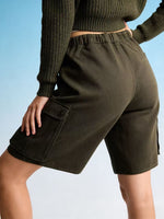 Person wearing olive green cargo shorts and a matching top against a light blue background
