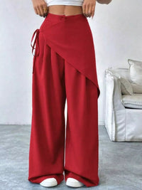 Red wide-leg pants worn by a person in a minimalistic room.