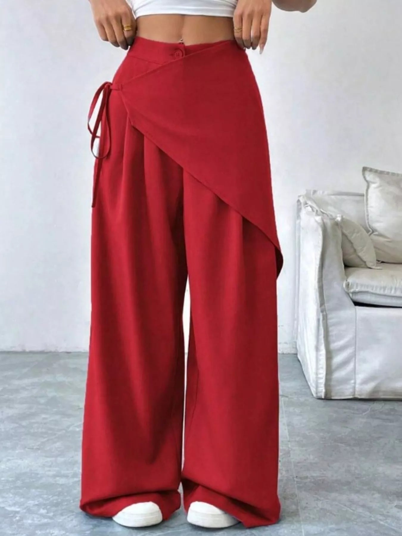 Red wide-leg pants worn by a person in a minimalistic room.