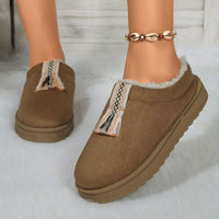 Brown slippers with decorative trim worn by a person on a light background