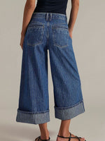 Person wearing blue wide-leg jeans on a plain background