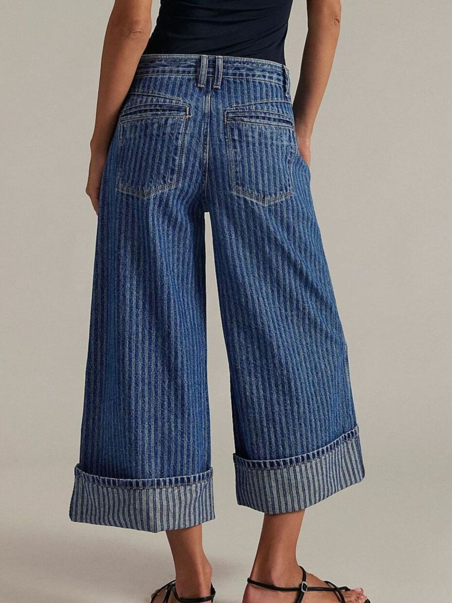 Person wearing blue wide-leg jeans on a plain background