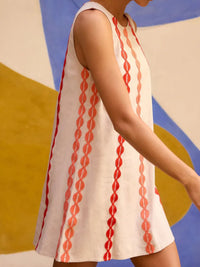 Woman wearing a sleeveless dress with red pattern against a colorful abstract background