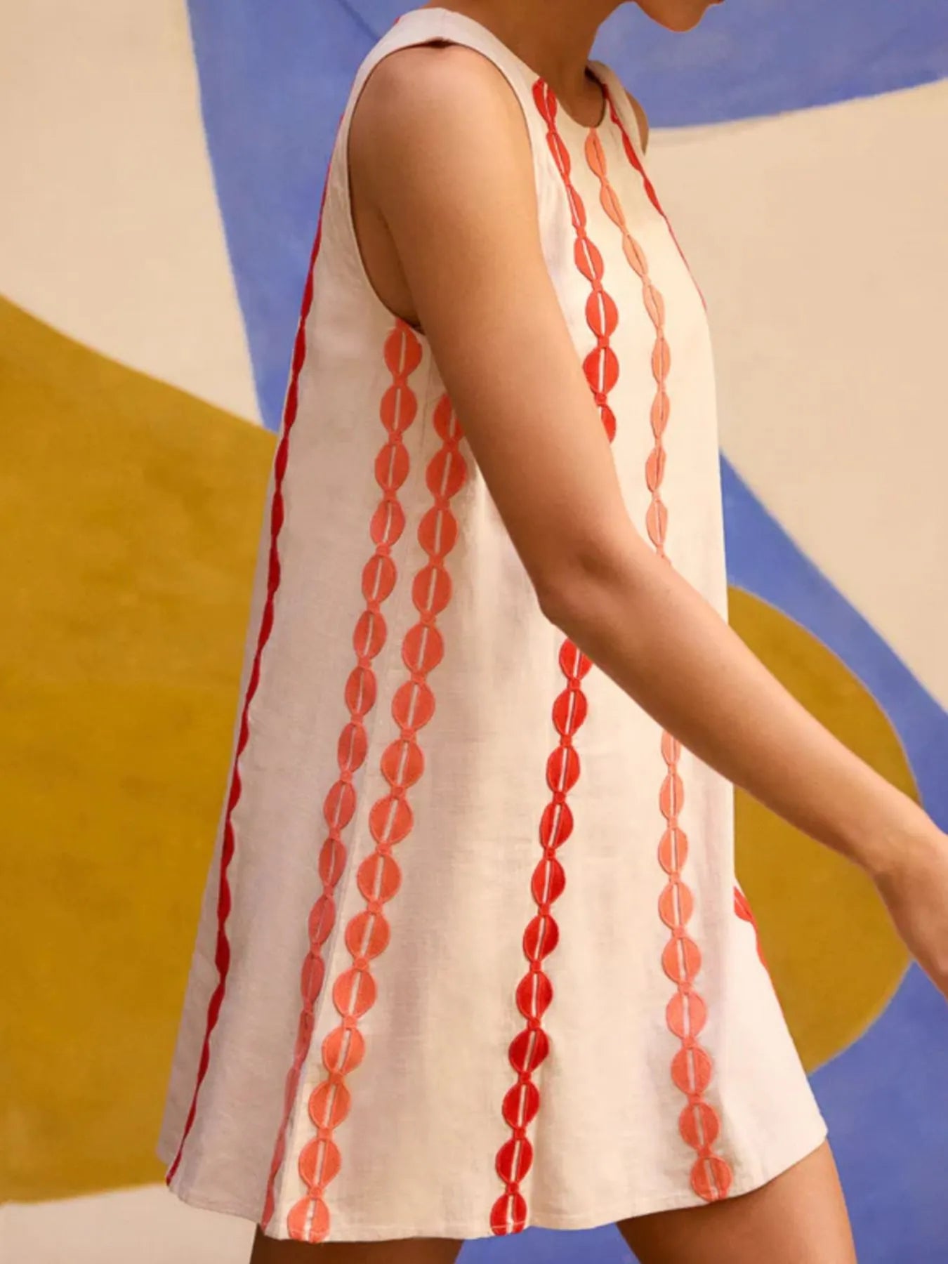 Woman wearing a sleeveless dress with red pattern against a colorful abstract background