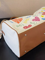 Children's drawing on a brown and white bag with colorful hearts and text.