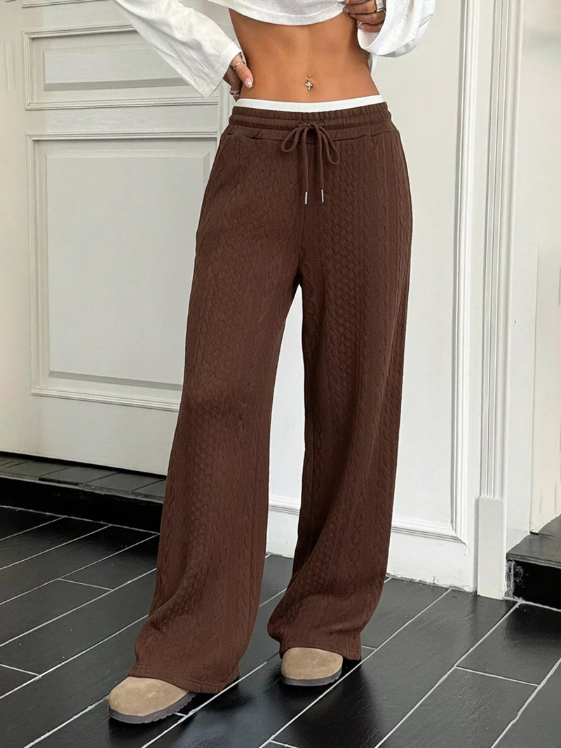 Brown wide-leg pants worn by a person indoors on a black tiled floor.
