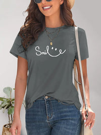Woman wearing a gray t-shirt with 'Smile' text and smiling.