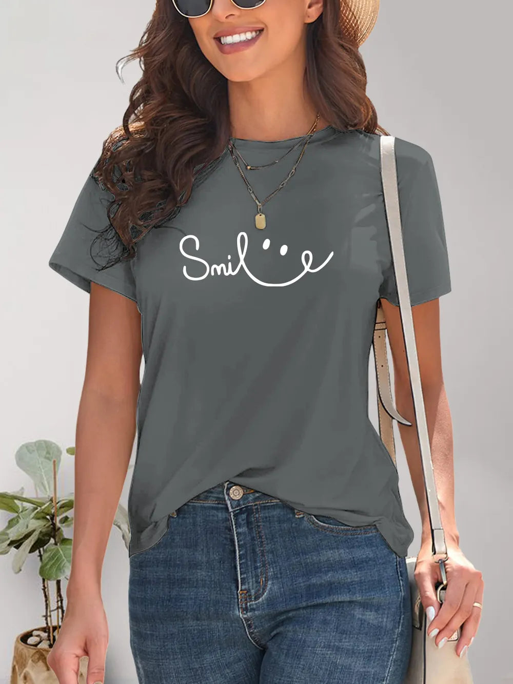 Woman wearing a gray t-shirt with 'Smile' text and smiling.