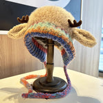Colorful knitted hat with moose ears on a mannequin head against a neutral background