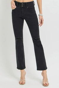 Black distressed jeans worn by a person on a white background