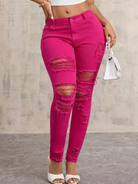 Person wearing bright pink ripped jeans against a neutral background